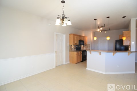 A living room with a television and a kitchen area in the background.