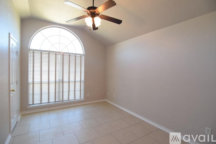 A room with a ceiling fan and a window with blinds.