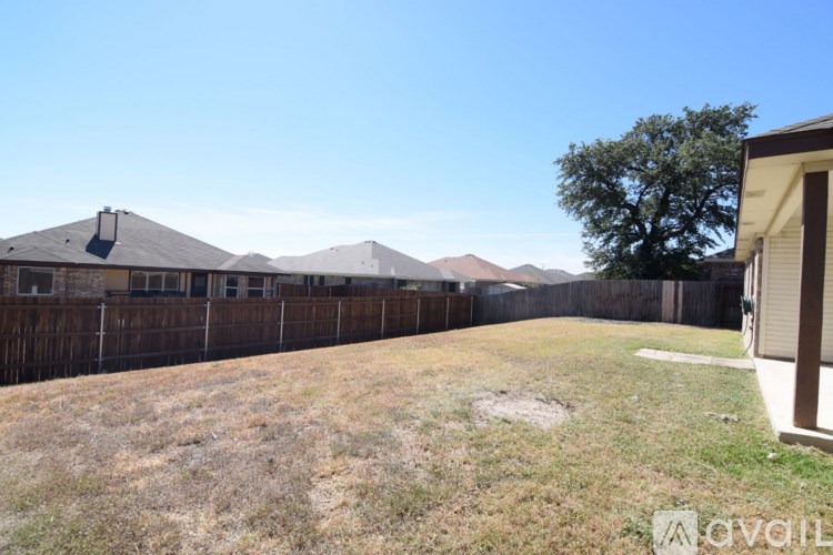 A backyard with a fence and a tree.