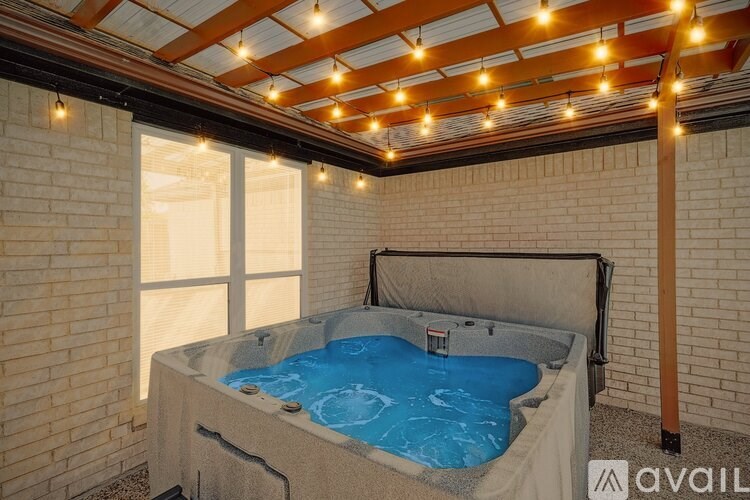 A hot tub is installed in a room with a wooden ceiling and brick walls.