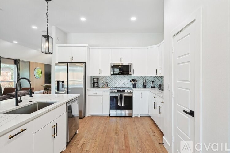 A modern kitchen with white cabinets and a wooden floor.