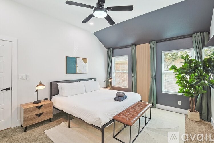 A bedroom with a bed, a ceiling fan, and a potted plant.