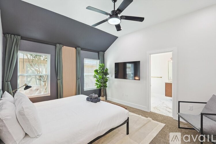 A bedroom with a bed, a ceiling fan, and a chair.