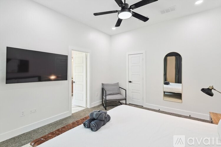 A bedroom with a bed, a ceiling fan, and a mirrored cabinet.