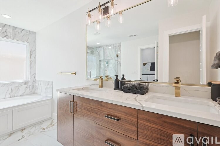 A bathroom with a marble tub surround and a vanity with a marble countertop.