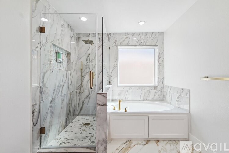A bathroom with marble tiles and a white tub.