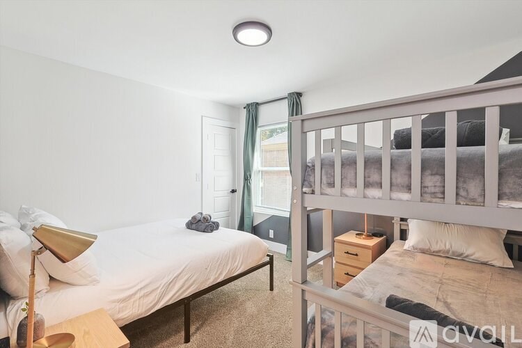 A bedroom with a white bed and a bunk bed.