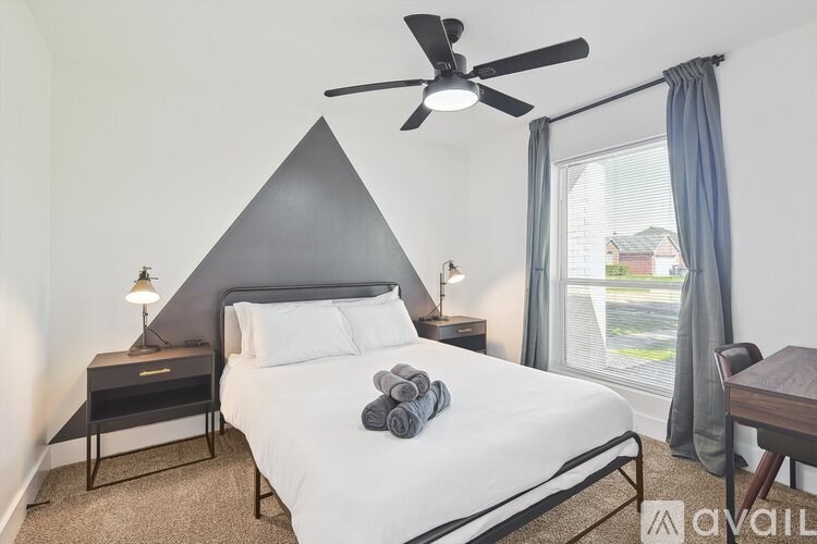 A bedroom with a bed, nightstand, and a ceiling fan.