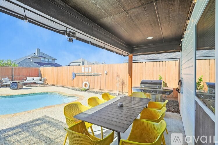 A patio with a table and chairs overlooking a pool.