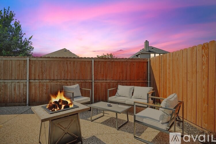 A patio with a fire pit and chairs.