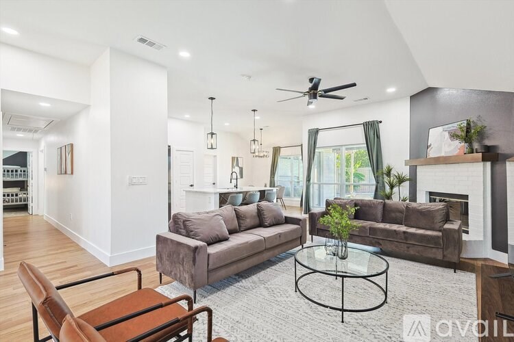 A living room with a brown couch, a glass coffee table, and a fireplace.