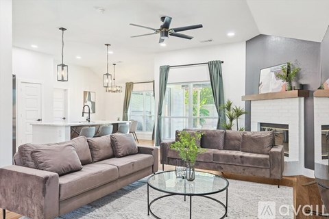 A living room with a brown couch and a glass coffee table.
