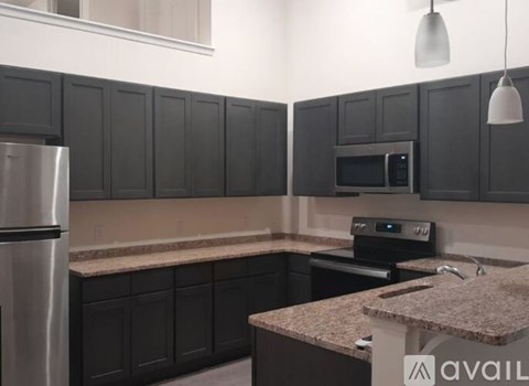 A kitchen with black cabinets and a granite countertop.
