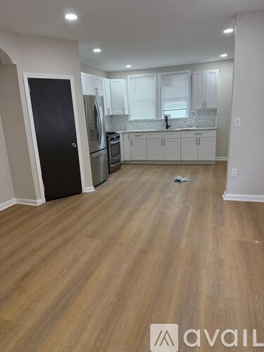 A kitchen with white cabinets and a black door.