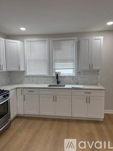 A kitchen with white cabinets and a marble countertop.
