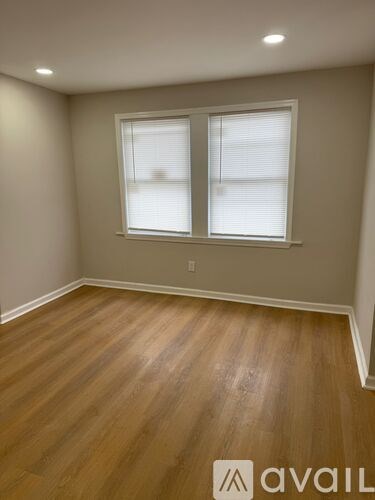 A room with wooden flooring and a window with blinds.