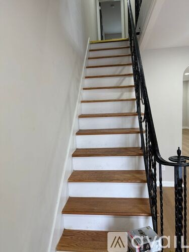 A staircase with wooden steps and a black railing.