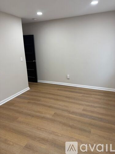 A room with wooden flooring and a black wardrobe.