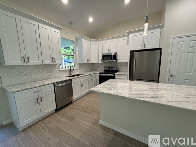 A kitchen with white cabinets and a marble countertop.