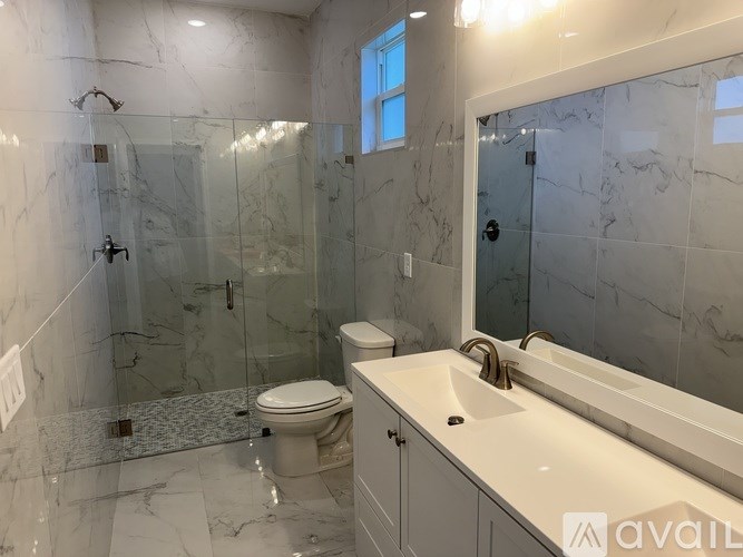 A bathroom with marble tiles and a glass shower stall.