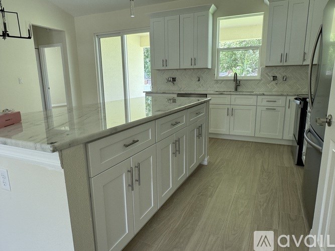 A kitchen with white cabinets and a marble countertop.