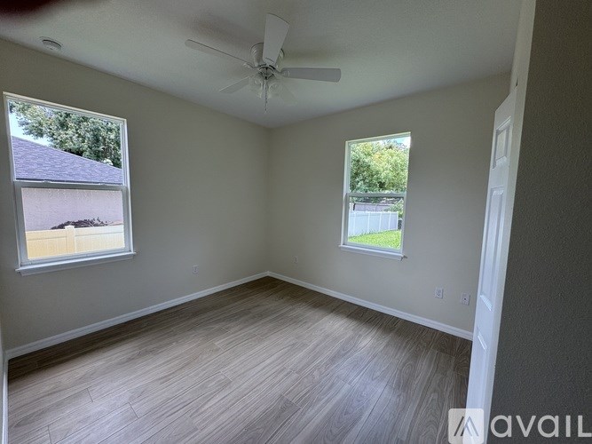A room with a ceiling fan and two windows.