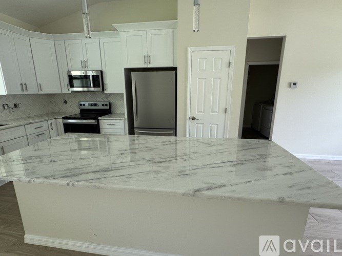 A kitchen with a marble countertop and stainless steel appliances.
