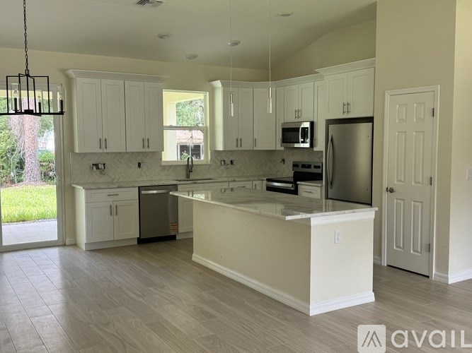 A kitchen with white cabinets and a large island.