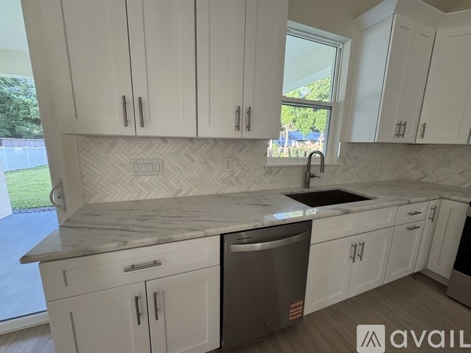A kitchen with white cabinets and a marble countertop.