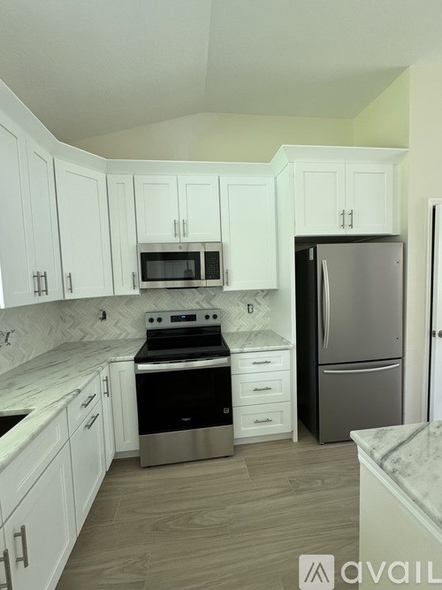 A kitchen with white cabinets and a marble countertop.
