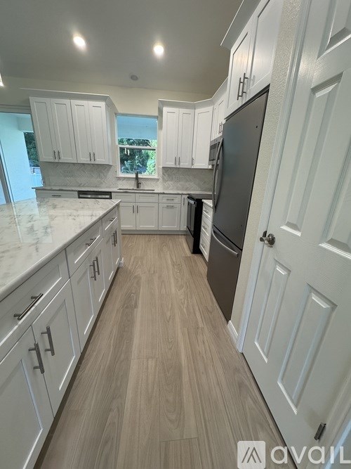 A kitchen with white cabinets and a black fridge.