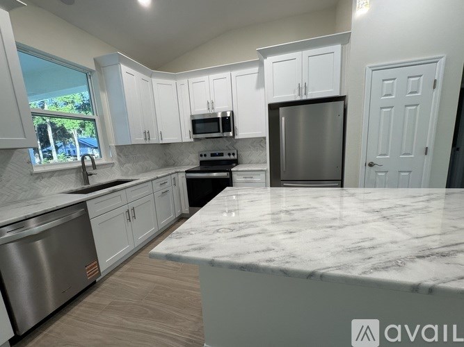 A kitchen with white cabinets and a marble countertop.