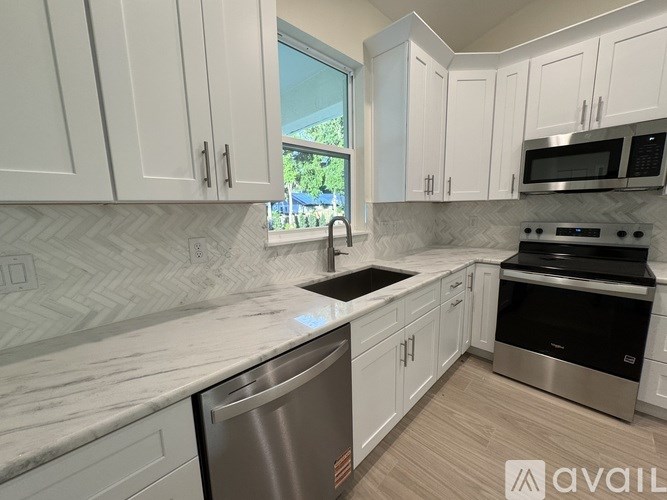 A kitchen with white cabinets and a marble countertop.