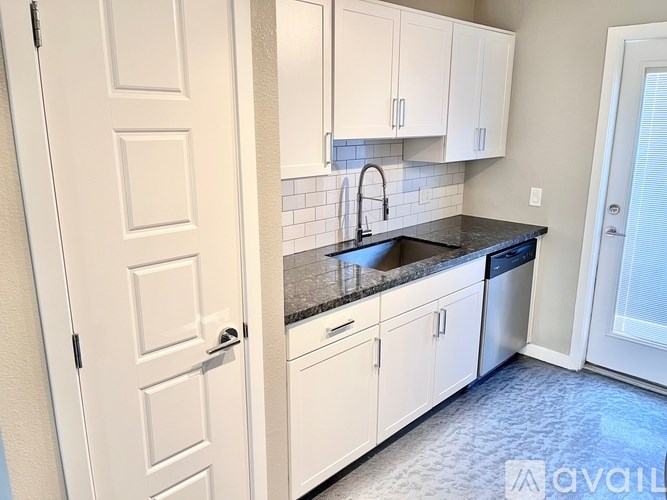 A kitchen with white cabinets and a black countertop.