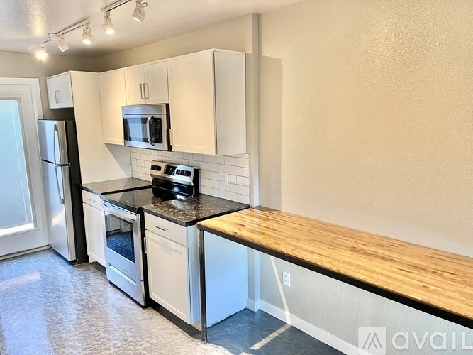 A kitchen with white cabinets and a wooden countertop.