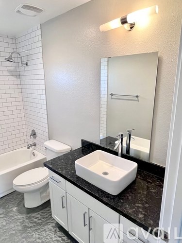 A white bathroom with black granite countertops and a white sink.