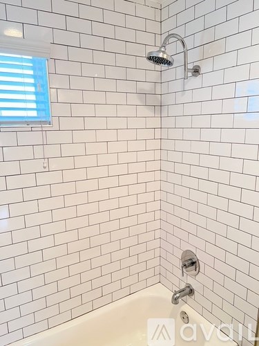 A white tiled shower with a glass door and a window.