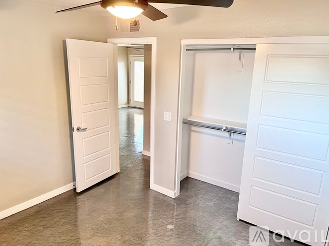 A room with a ceiling fan and two open doors.