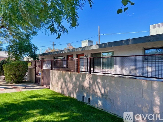 A modern house with a red fence and a green lawn.