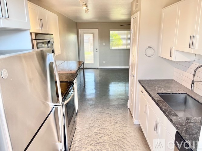 A kitchen with a refrigerator, sink, and cabinets.
