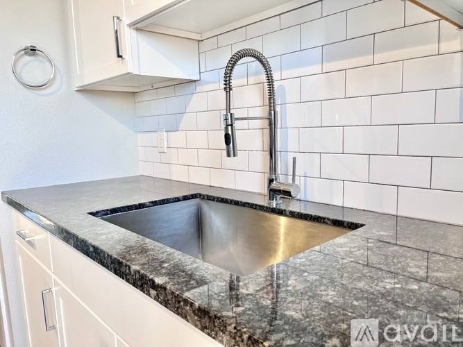 A kitchen sink with a granite countertop and a chrome faucet.