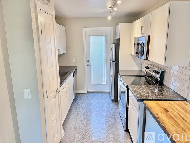A kitchen with white cabinets and black countertops.