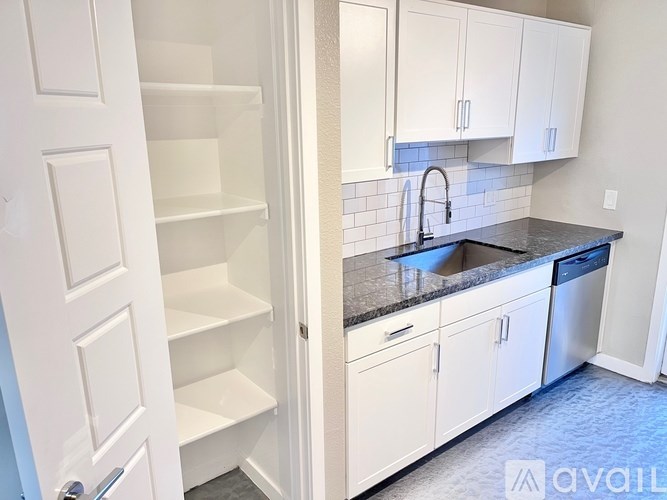 A kitchen with white cabinets and a black countertop.
