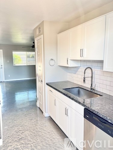 A kitchen with white cabinets and a black countertop.