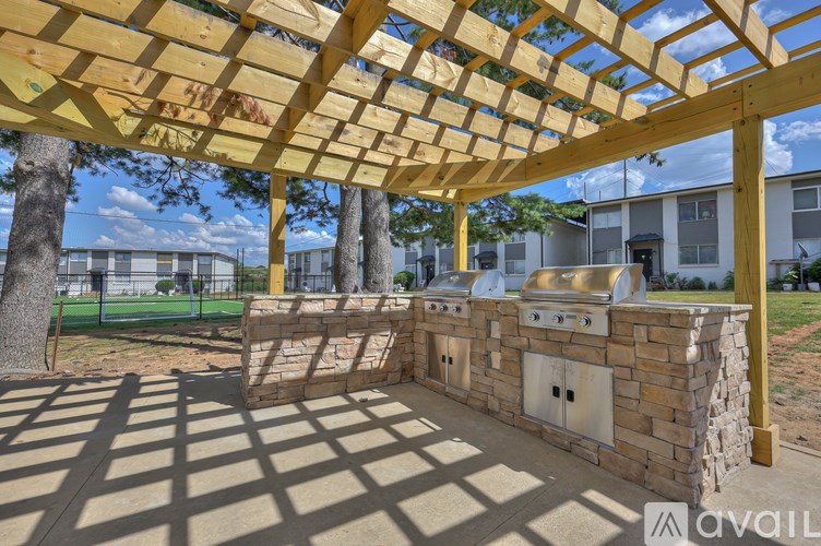 A wooden pergola with a stone wall underneath it.