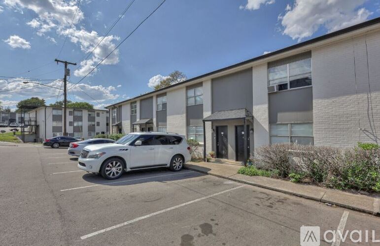 A white car is parked in a parking lot in front of a building.