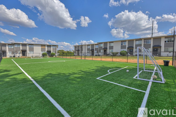 A soccer field with a goal post and a building in the background.