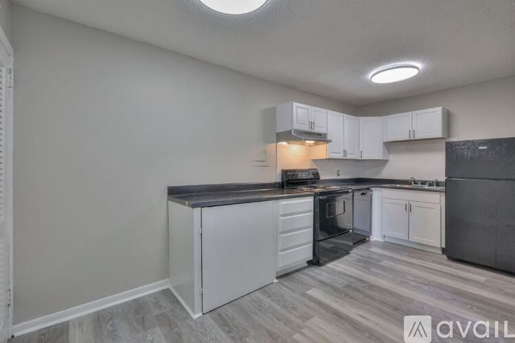 A kitchen with white cabinets and a black countertop.