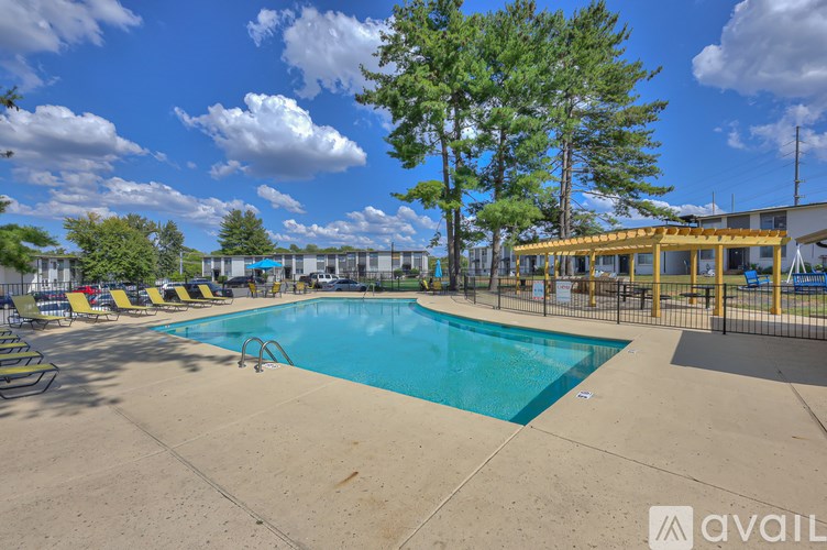 A large outdoor swimming pool surrounded by trees and lounge chairs.