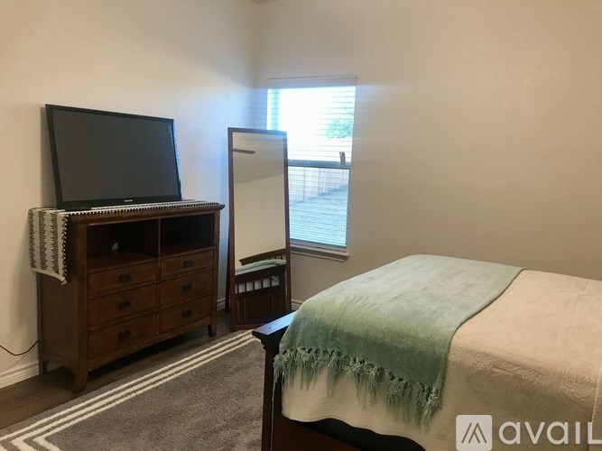 A bedroom with a bed, a television, and a dresser.